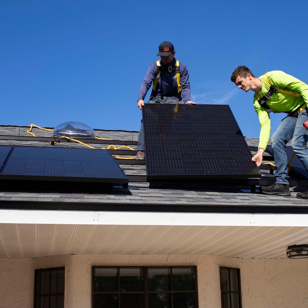 Deux installateurs de panneaux solaires équipés d'un équipement de sécurité intervenant sur un toit pour installer des panneaux photovoltaïques et réaliser des économies d'énergie dans l'hérault.