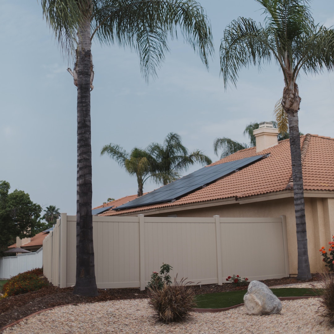 Maison du sud de la France avec panneaux solaires posés sur le toit pour réaliser des économies d'énergie dans l'hérault. Des palmiers sont au premier plan.